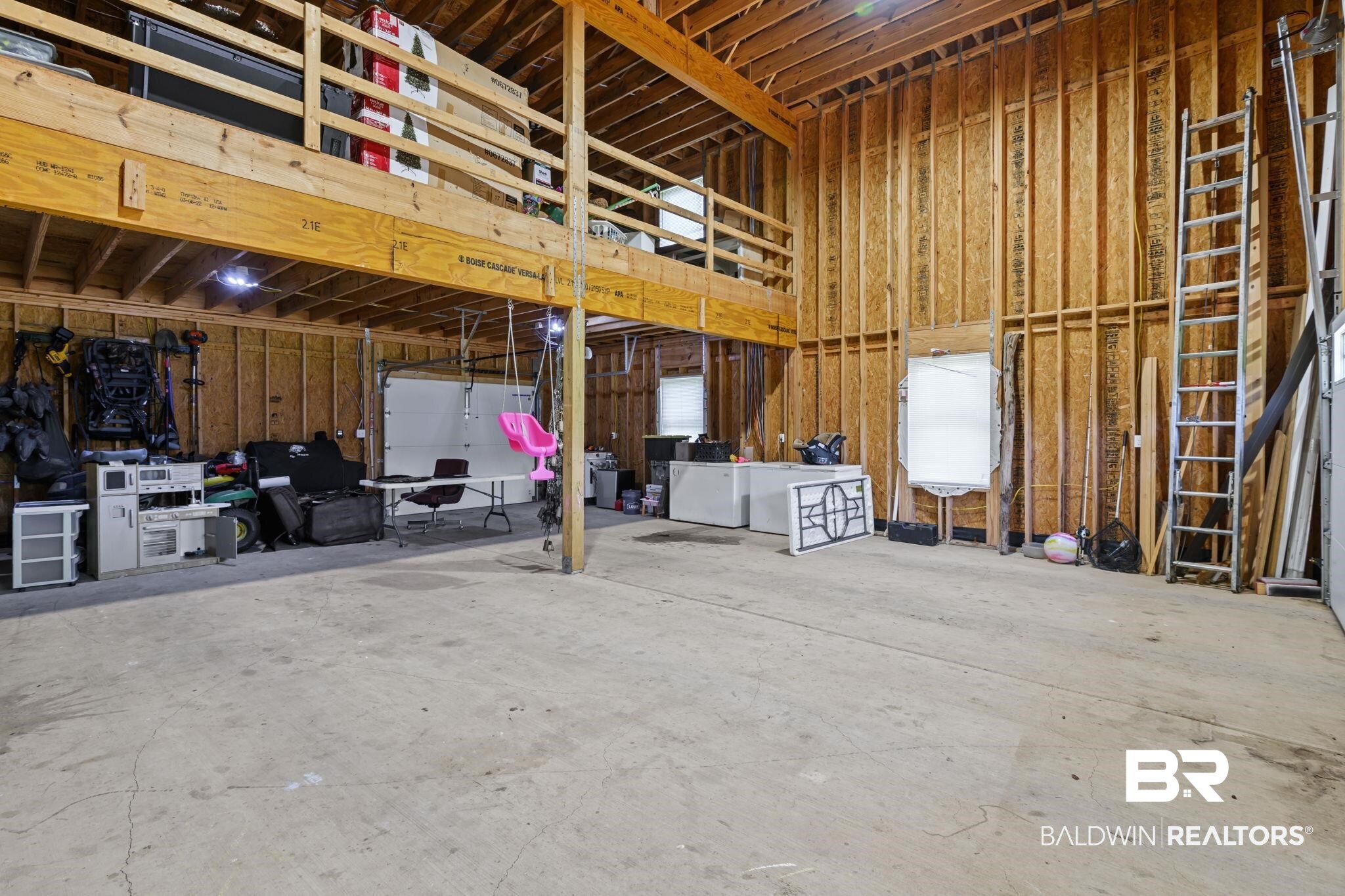 11025 Creax Road Axis, AL 36505 - Photo 35 of 45 Spacious multi-level garage featuring a concrete floor, exposed wood framing, and an upper storage loft with a railing