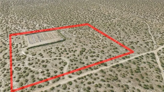 a view of a dry yard with wooden fence