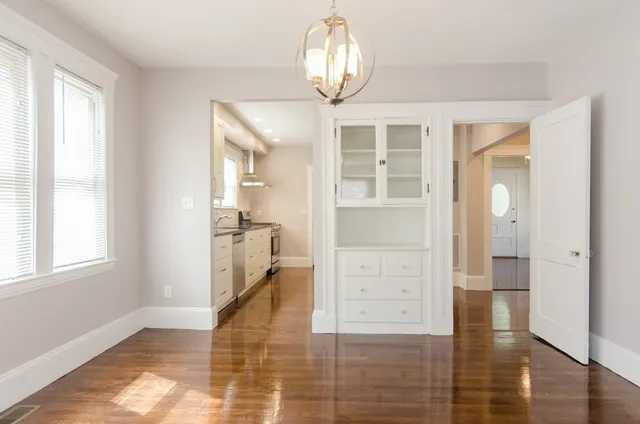 a view of a hallway with wooden floor and a chandelier