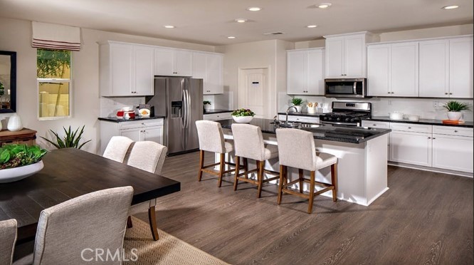 14080 Versimo Lane Beaumont, CA 92223 - Photo 4 of 20 a kitchen with stainless steel appliances granite countertop a stove a sink a microwave a dining table and chairs with wooden floor