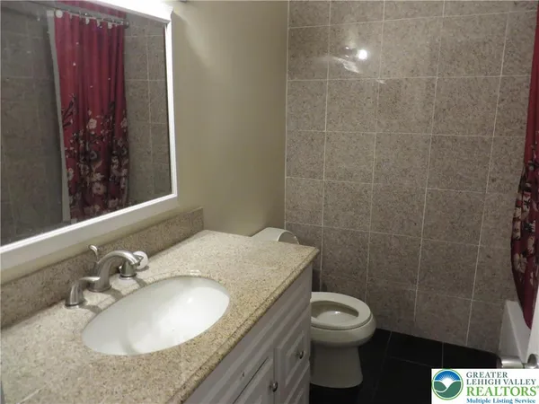 a bathroom with a granite countertop sink toilet and a mirror
