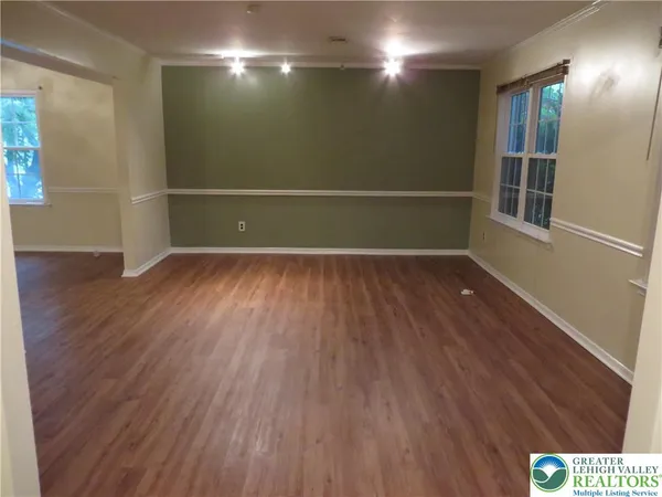 a view of an empty room with wooden floor and windows