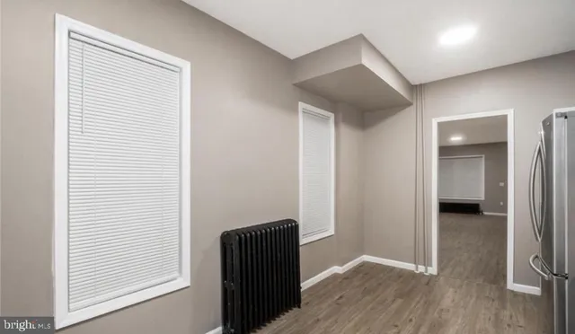 an empty room with wooden floor closet and windows