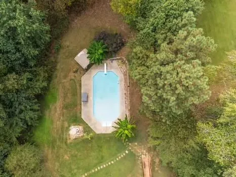 an aerial view of a house with a yard and trees all around