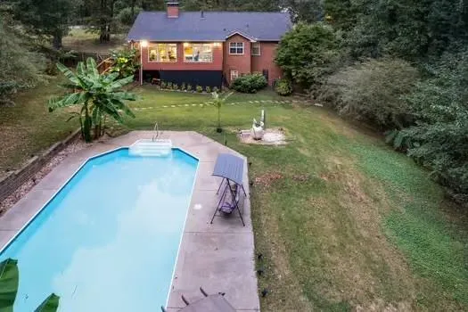 a view of a house with a swimming pool and a yard