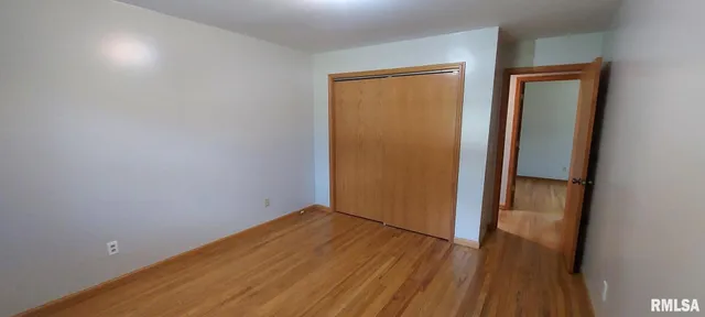 an empty room with wooden floor and closet