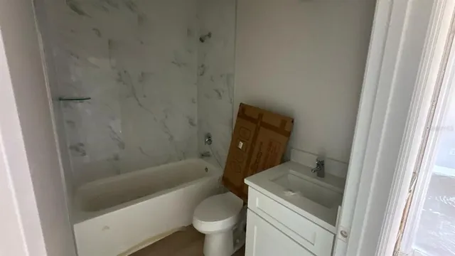 a bathroom with a granite countertop toilet a sink and bathtub