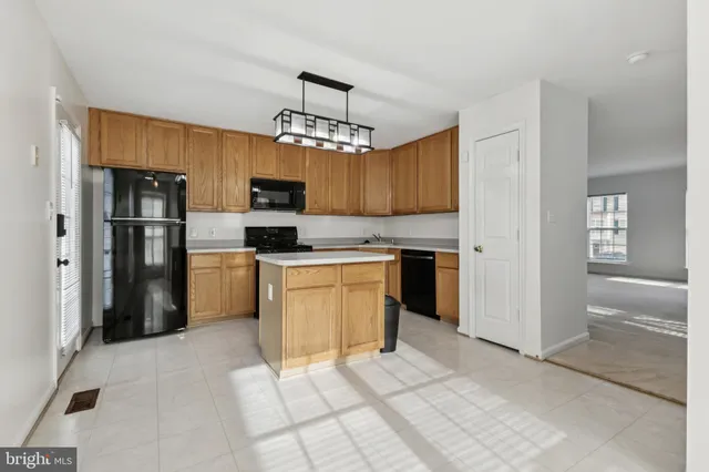 a kitchen with kitchen island granite countertop a refrigerator oven a sink dishwasher and white cabinets with wooden floor