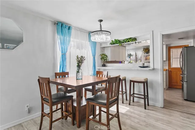 a dining room with wooden floor a chandelier a wooden table and chairs