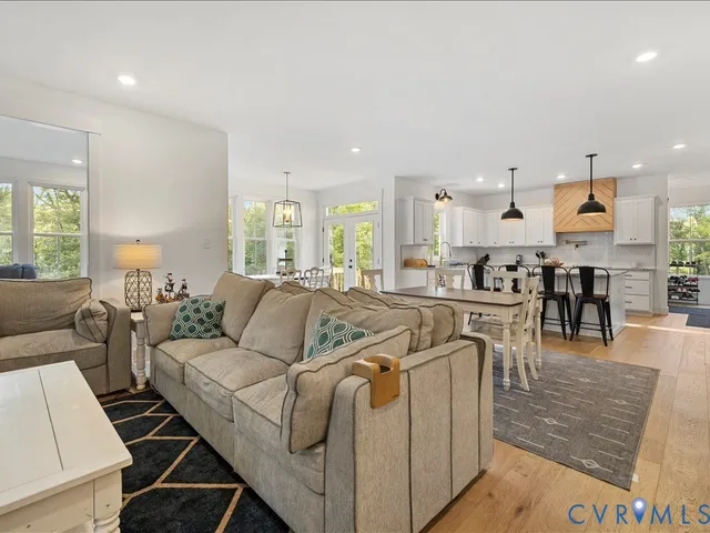 a kitchen with stainless steel appliances granite countertop a stove a sink a microwave a dining table and chairs with wooden floor