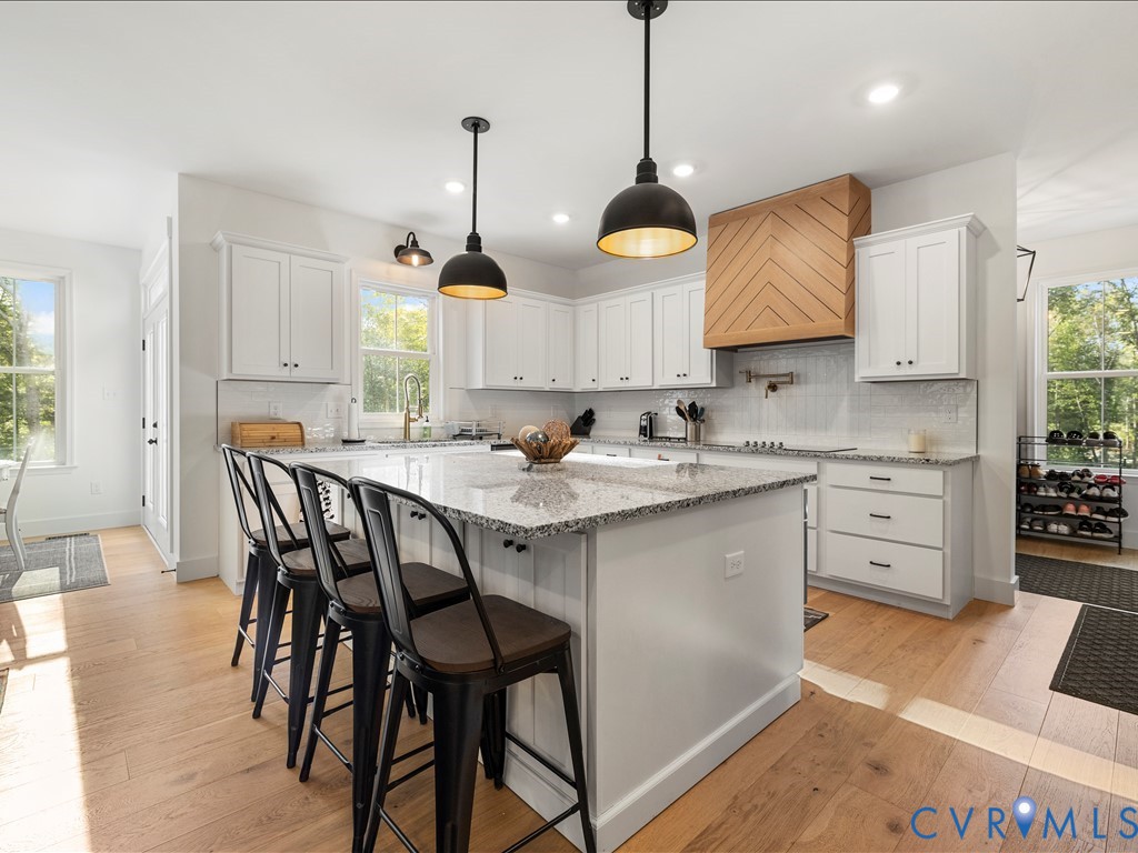 4021 Tredon Road Mechanicsville, VA 23111 - Photo 16 of 50 a kitchen with stainless steel appliances granite countertop a stove a sink a microwave a dining table and chairs with wooden floor