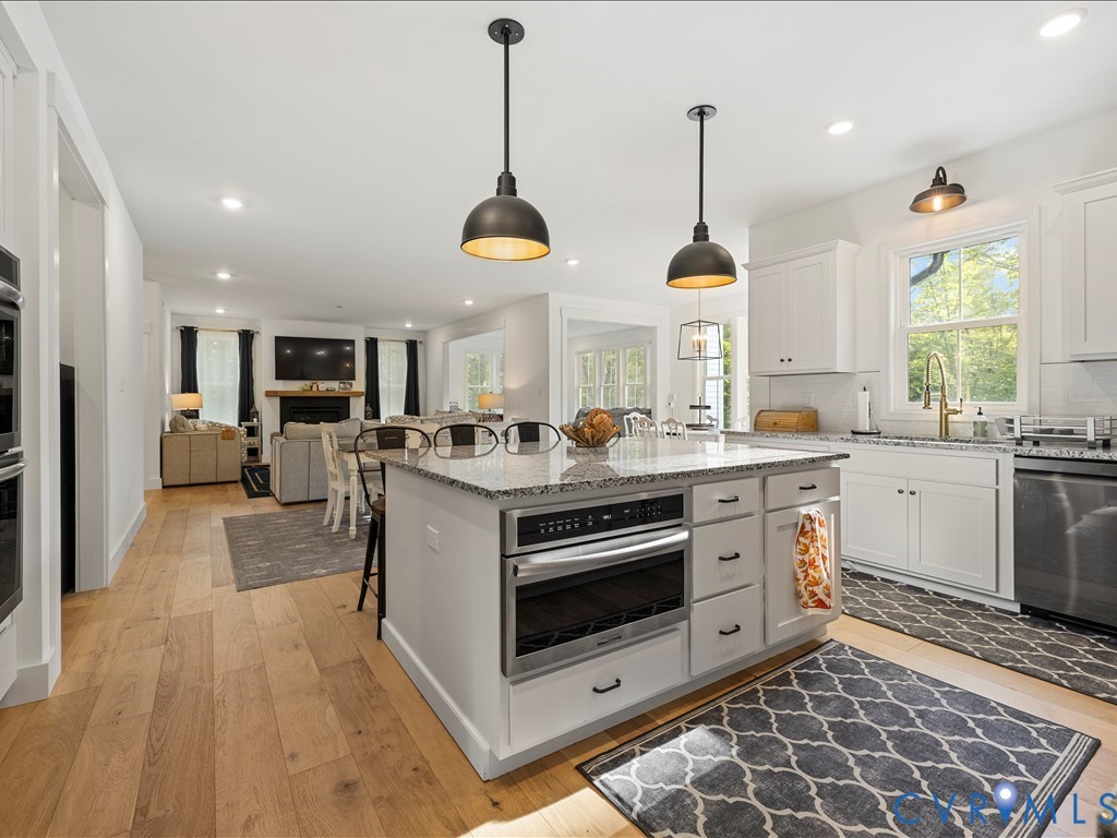 4021 Tredon Road Mechanicsville, VA 23111 - Photo 17 of 50 a kitchen with stainless steel appliances granite countertop a stove a sink dishwasher a refrigerator and a dining table with wooden floor