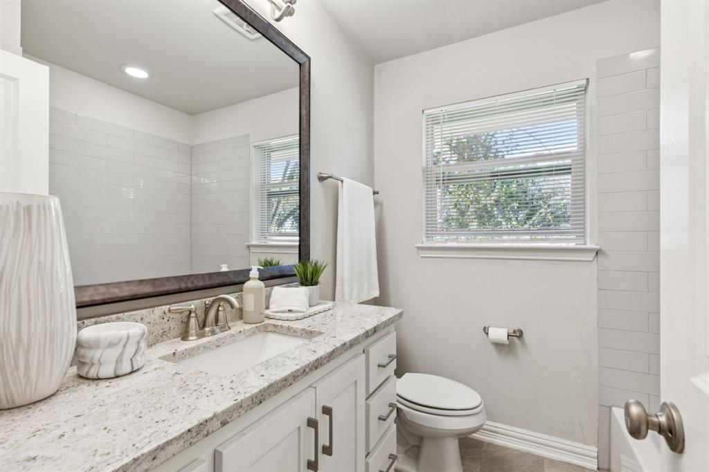 9363 Angora Street Dallas, TX 75218 - Photo 6 of 10 a bathroom with a granite countertop toilet a sink and a mirror