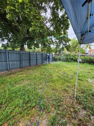 a view of a backyard with a tree and wooden fence