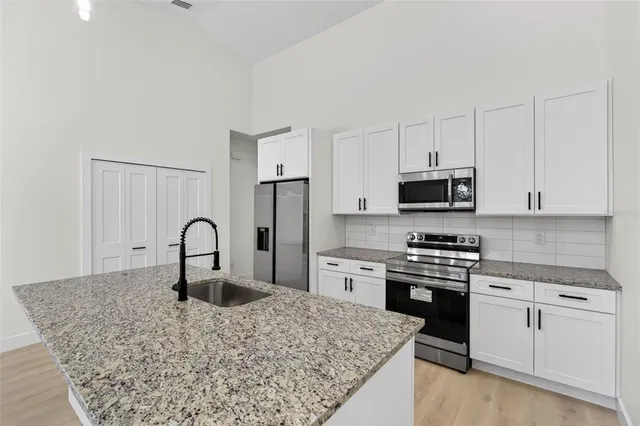 a kitchen with white cabinets and appliances