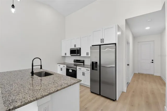 a kitchen with refrigerator a stove and a sink