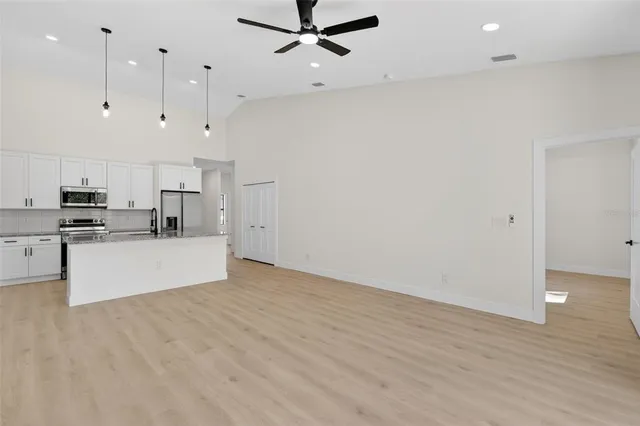 a view of a kitchen with kitchen island a sink wooden floor and stainless steel appliances