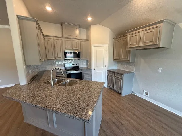 a kitchen with kitchen island granite countertop a sink cabinets and stainless steel appliances