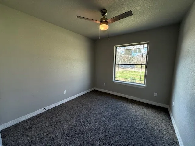 an empty room with a window and a fan