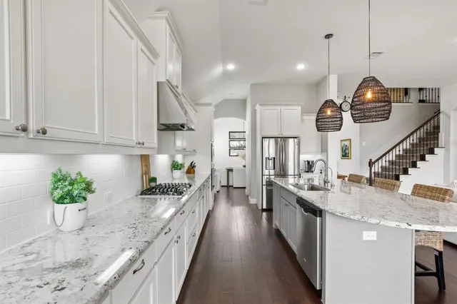 a kitchen with granite countertop a stove a sink a refrigerator and a counter space