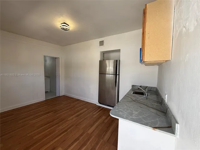 a kitchen with a granite countertop sink and refrigerator