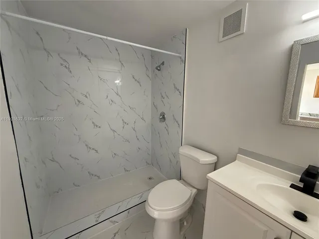 a white toilet sitting next to a bathroom sink and vanity