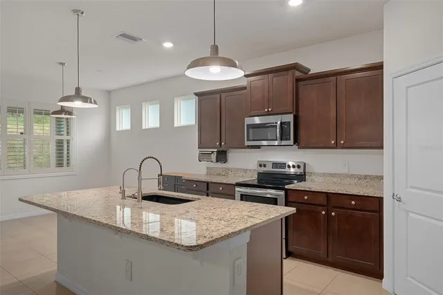 a kitchen with stainless steel appliances granite countertop a sink a stove a refrigerator and a oven with wooden floor