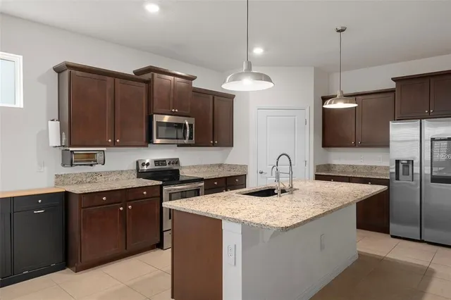 a kitchen with stainless steel appliances granite countertop a sink stove a refrigerator and a microwave