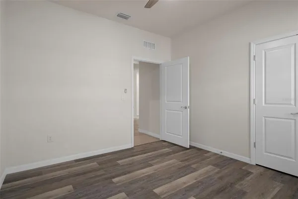 a view of an empty room with wooden floor and closet