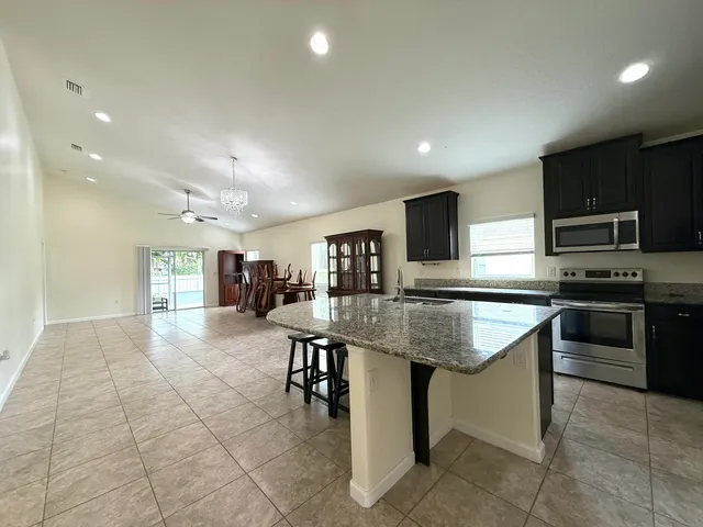 a kitchen with kitchen island stainless steel appliances a sink a counter top space appliances and cabinets
