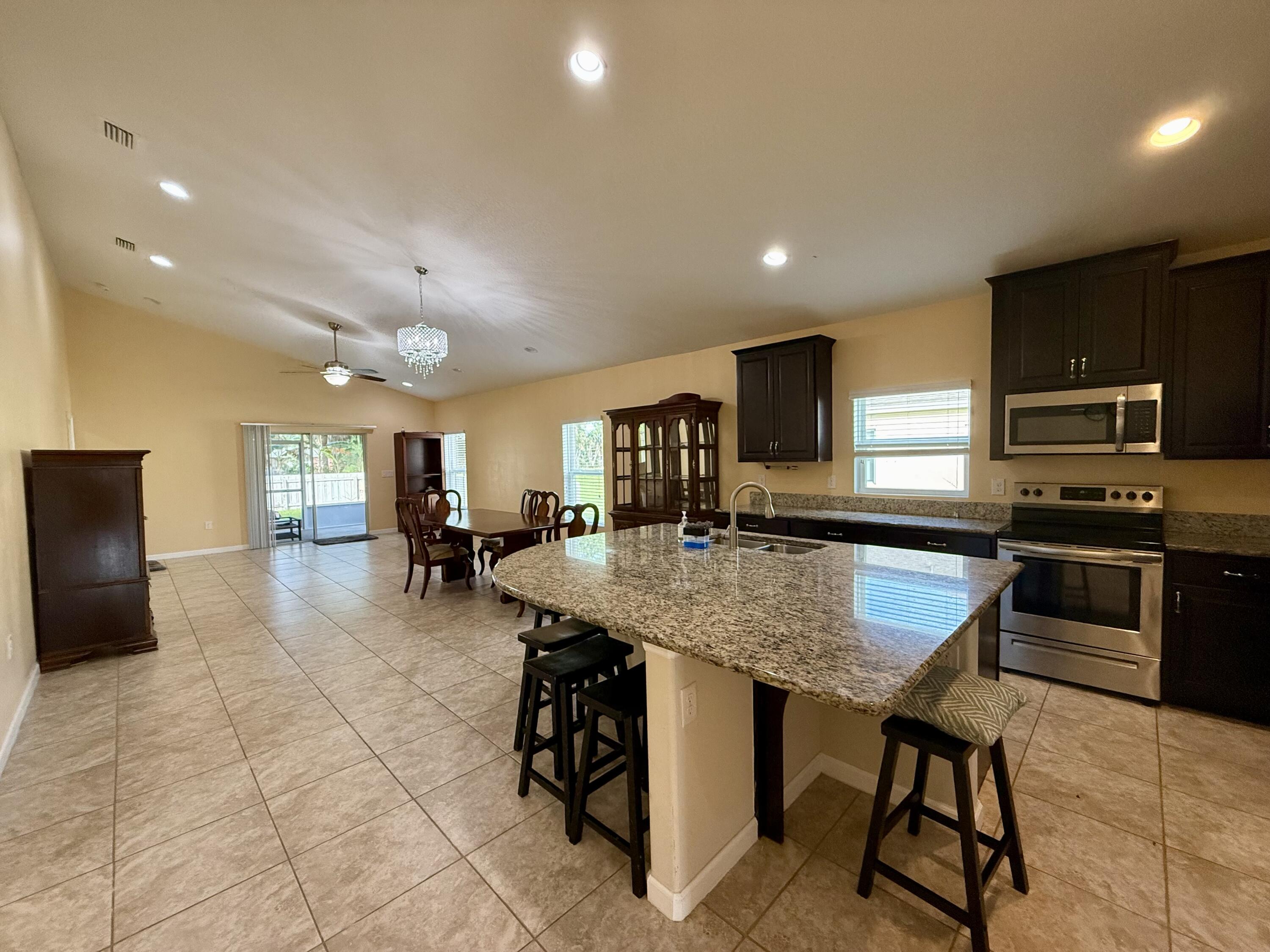 5997 Ridge Lake Circle Vero Beach, FL 32967 - Photo 3 of 14 a kitchen with stainless steel appliances granite countertop a stove a sink a microwave and a refrigerator
