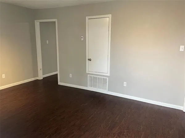 an empty room with wooden floor & closet area