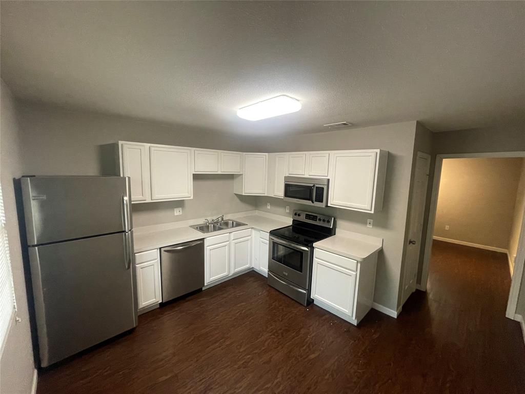 701 Elsbeth Street, Unit 201 Dallas, TX 75208 - Photo 9 of 14 a kitchen with a refrigerator a stove a microwave and wooden floor