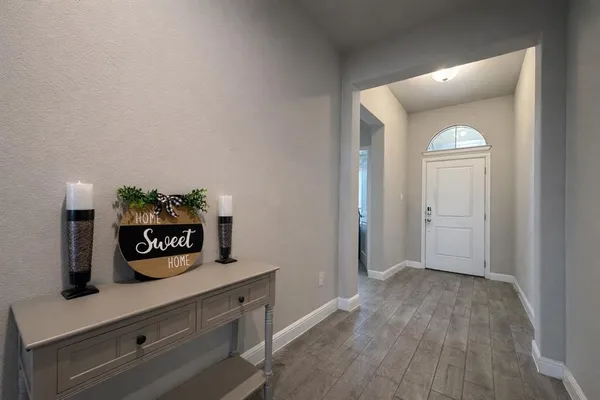a view of a hallway to a room with wooden floor and cabinet