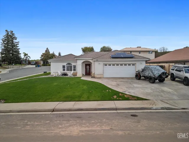 a car parked on the side of the road with a house in the background