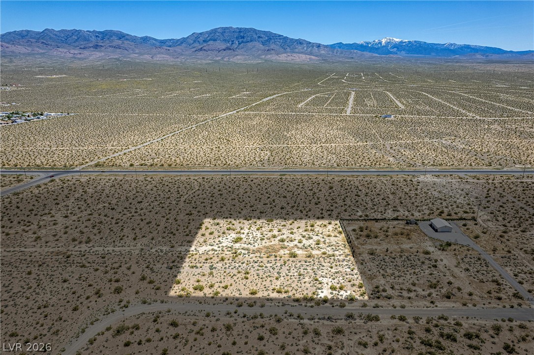 4861 Ruth Road Pahrump, NV 89060 - Photo 2 of 6 A vast, level desert lot awaits your vision, framed by distant mountains and a clear horizon.