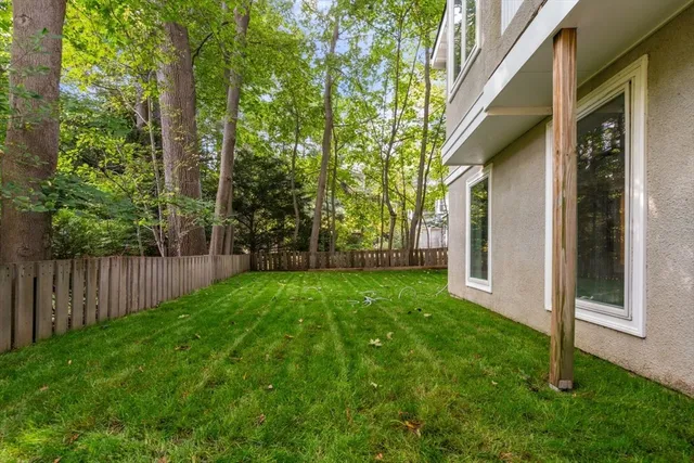 a view of a white house next to a yard with big trees