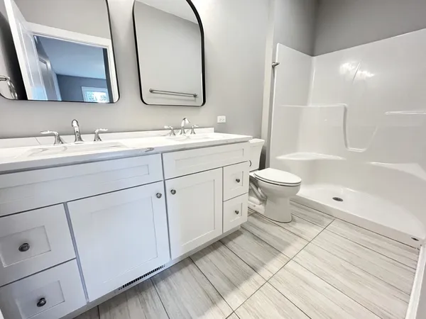a bathroom with a double vanity sink a toilet and a mirror