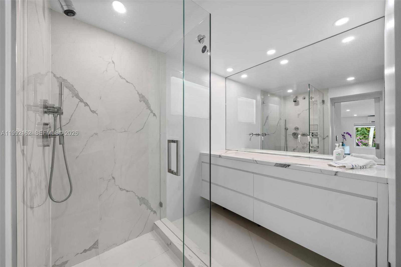 7531 Southwest 52nd Court Miami, FL 33143 - Photo 35 of 56 a bathroom with a double vanity sink a large mirror and shower