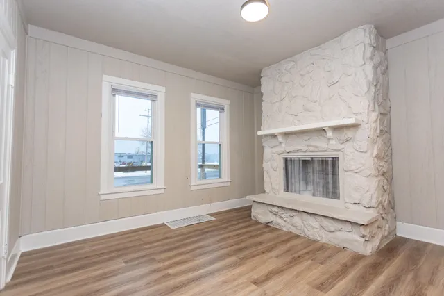 an empty room with wooden floor cabinet and windows