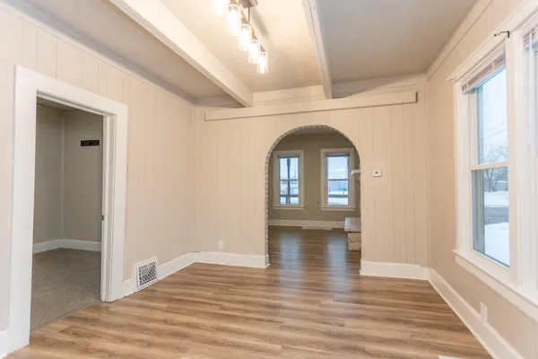 a view of empty room with window and wooden floor