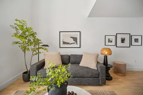 a living room with furniture flowers and a potted plant