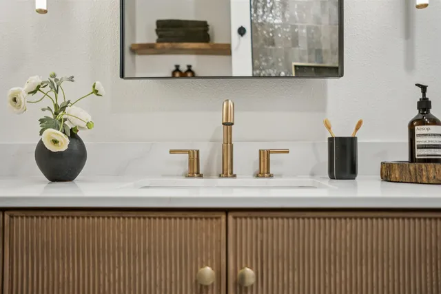 a bathroom with a sink a mirror and potted plant