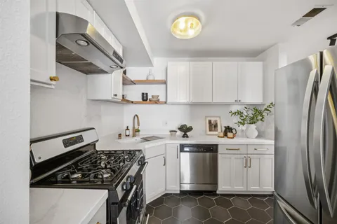 a kitchen with stainless steel appliances a stove a sink a refrigerator and cabinets