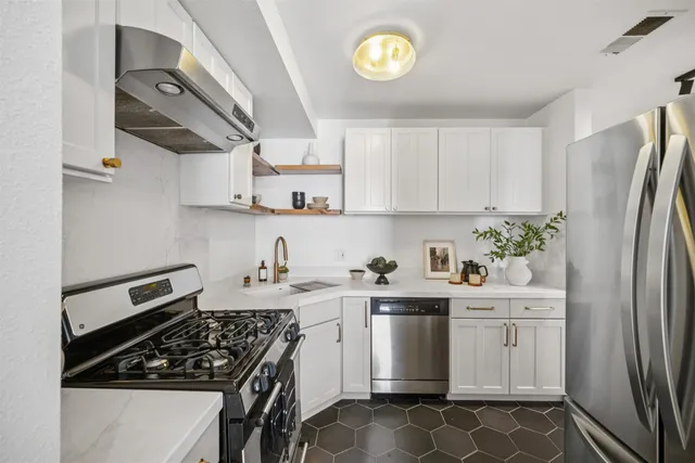 a kitchen with stainless steel appliances a stove a sink a refrigerator and cabinets