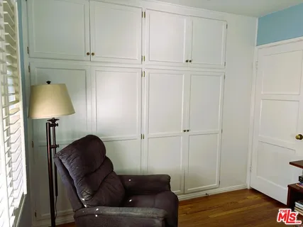 a bedroom with a bed next to a window with a chair