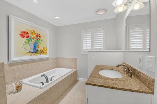 a bathroom with a granite countertop sink a mirror a vanity and a bathtub