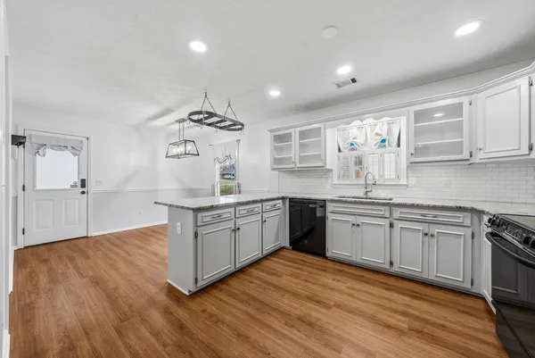 a kitchen with granite countertop a sink cabinets and wooden floor