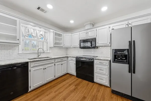 a kitchen with stainless steel appliances granite countertop a stove top oven a sink and a refrigerator