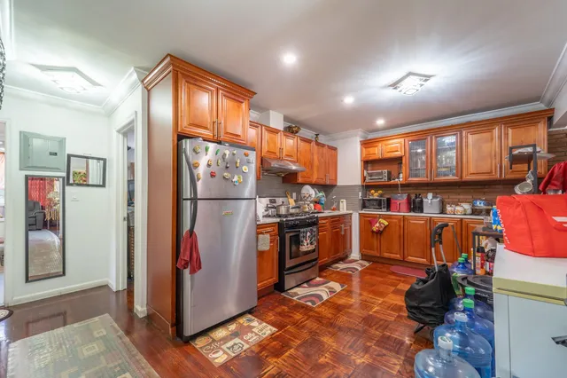a kitchen with stainless steel appliances granite countertop a refrigerator and a view of living room